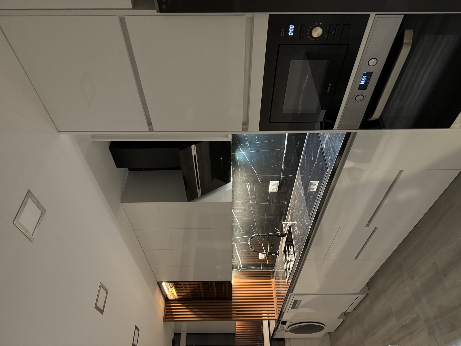 Cozinha lacada branca com bancada preta e lavandaria integrada — Corroios